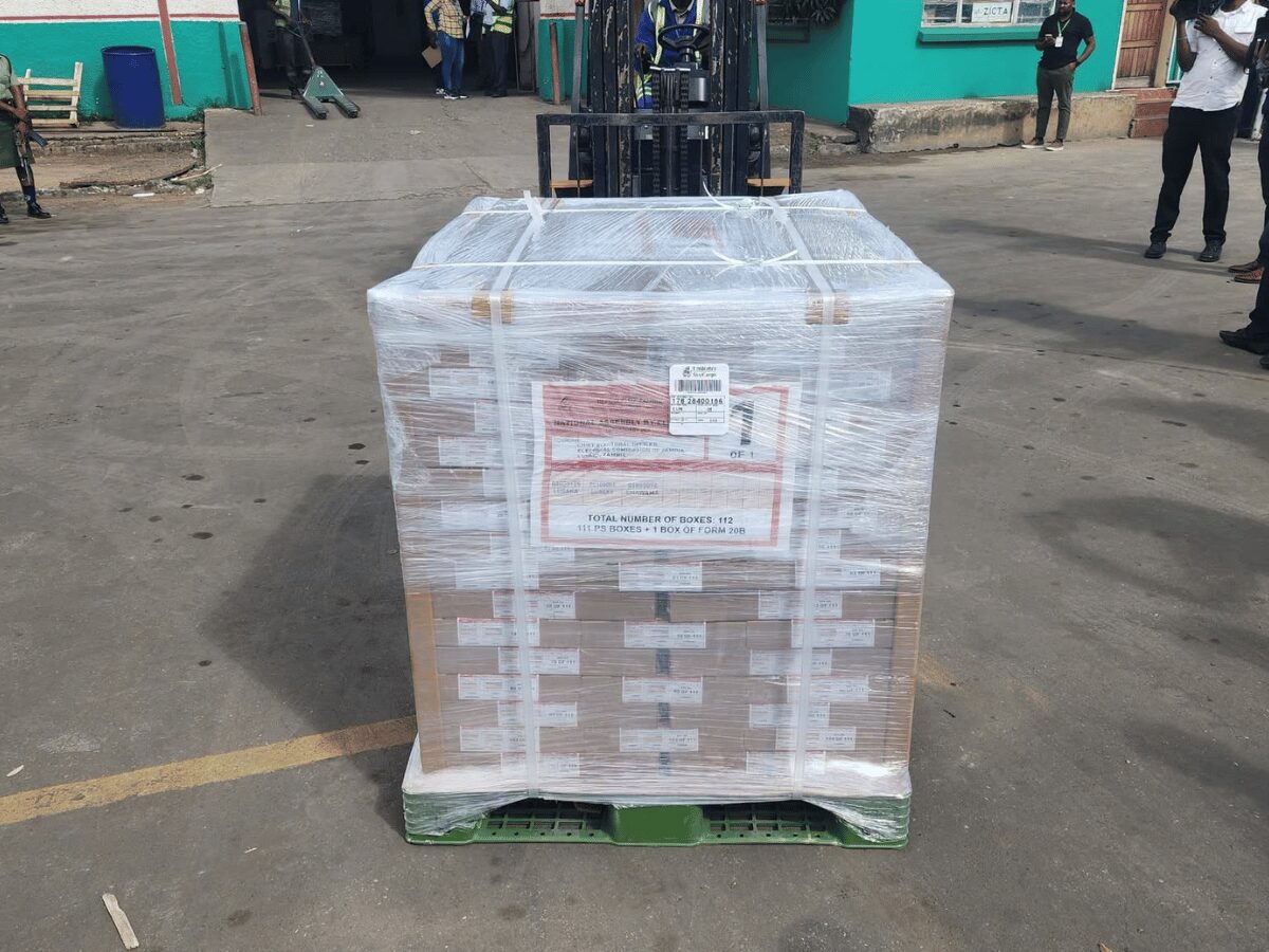 Pallet of ballot papers wrapped in plastic being offloaded by forklift in Livingstone, watched by police and stakeholders, ahead of Zambia's August 13 election