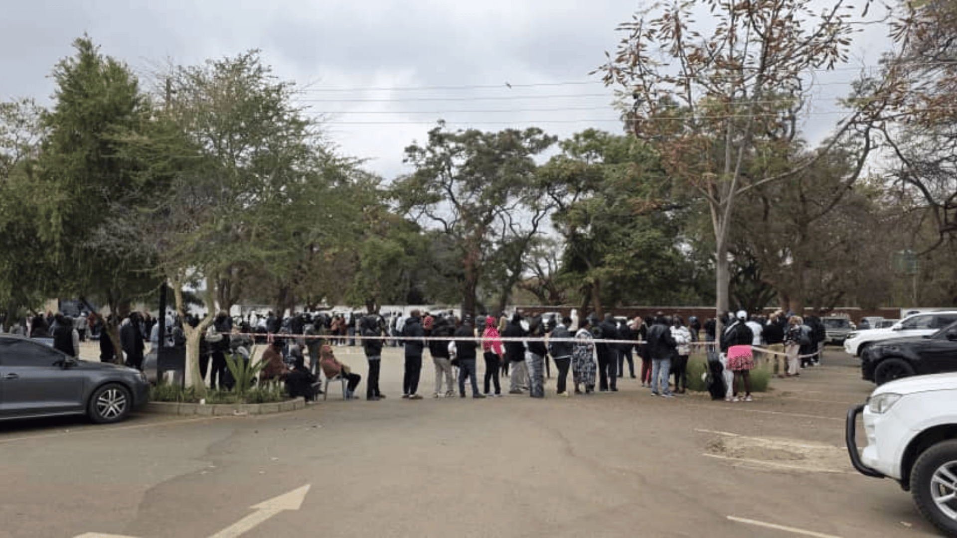 A long queue of voters stretches across the grounds at Lusaka Golf Club, with barrier tape managing crowd flow