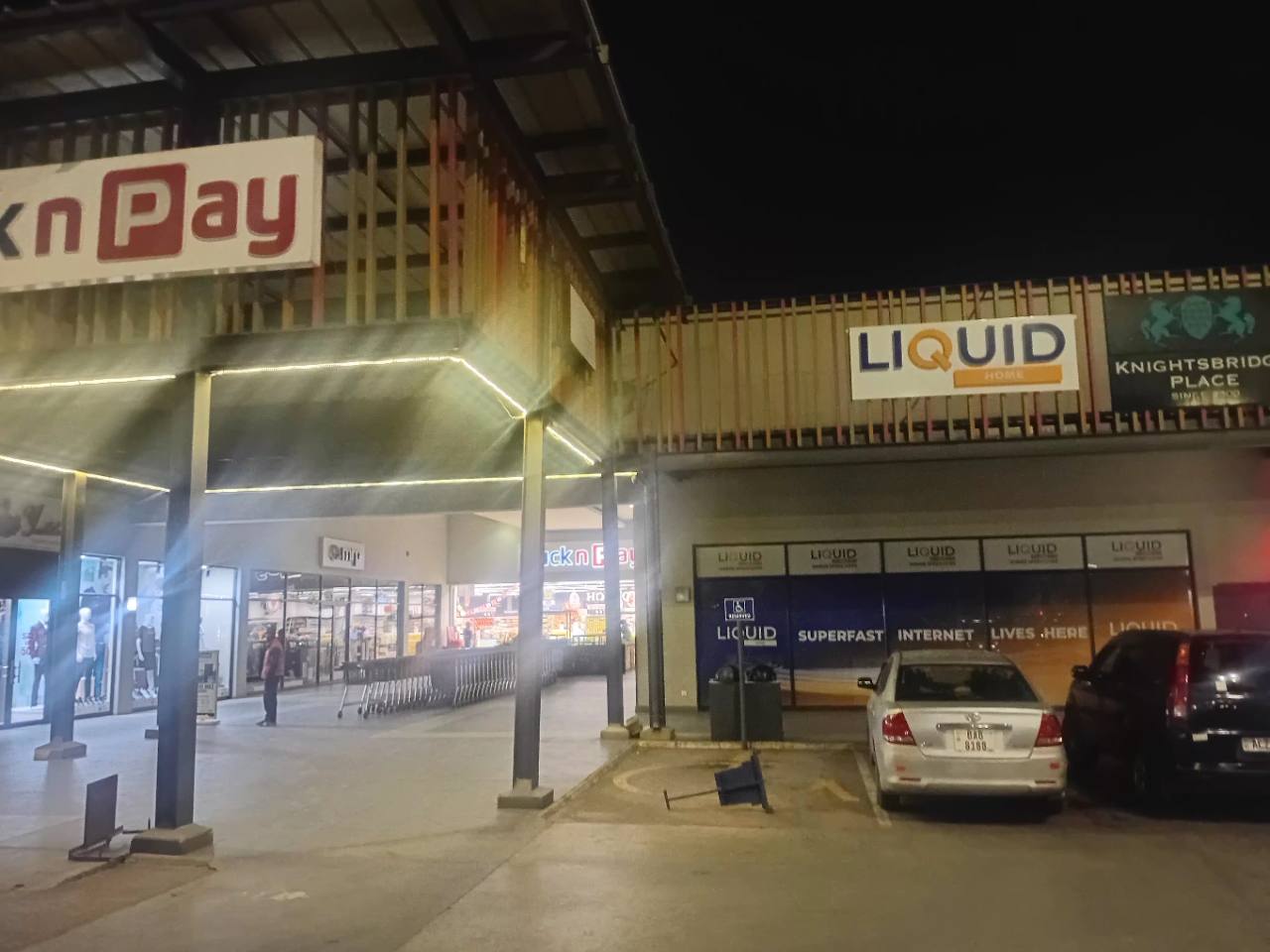 Pick n Pay entrance and Liquid Home storefront at Centro Mall in Kabulonga at night