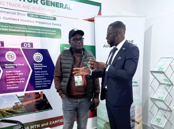 Charles Bukolo, Planner, engages a visitor at the Office of the Auditor General stand