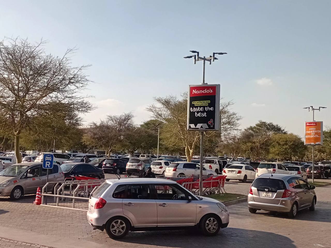 Parked vehicles, shopping trolleys and restaurant advertising at East Park Mall