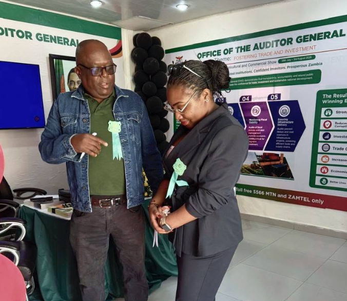 Faith Mponela, Planner, assists a visitor at the Office of the Auditor General stand