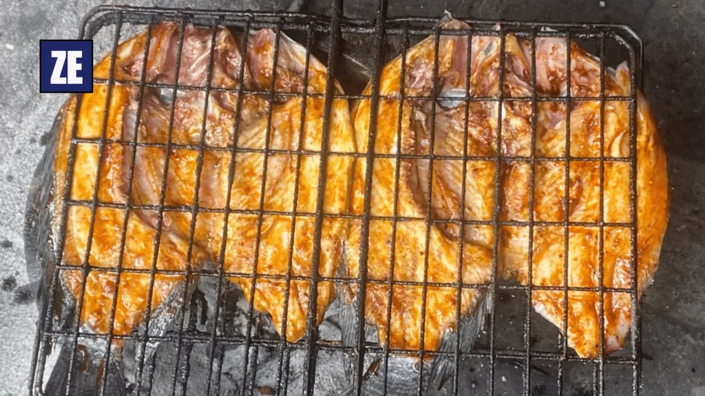 Seasoned whole fish cooking over charcoal at Longacres Market in Lusaka