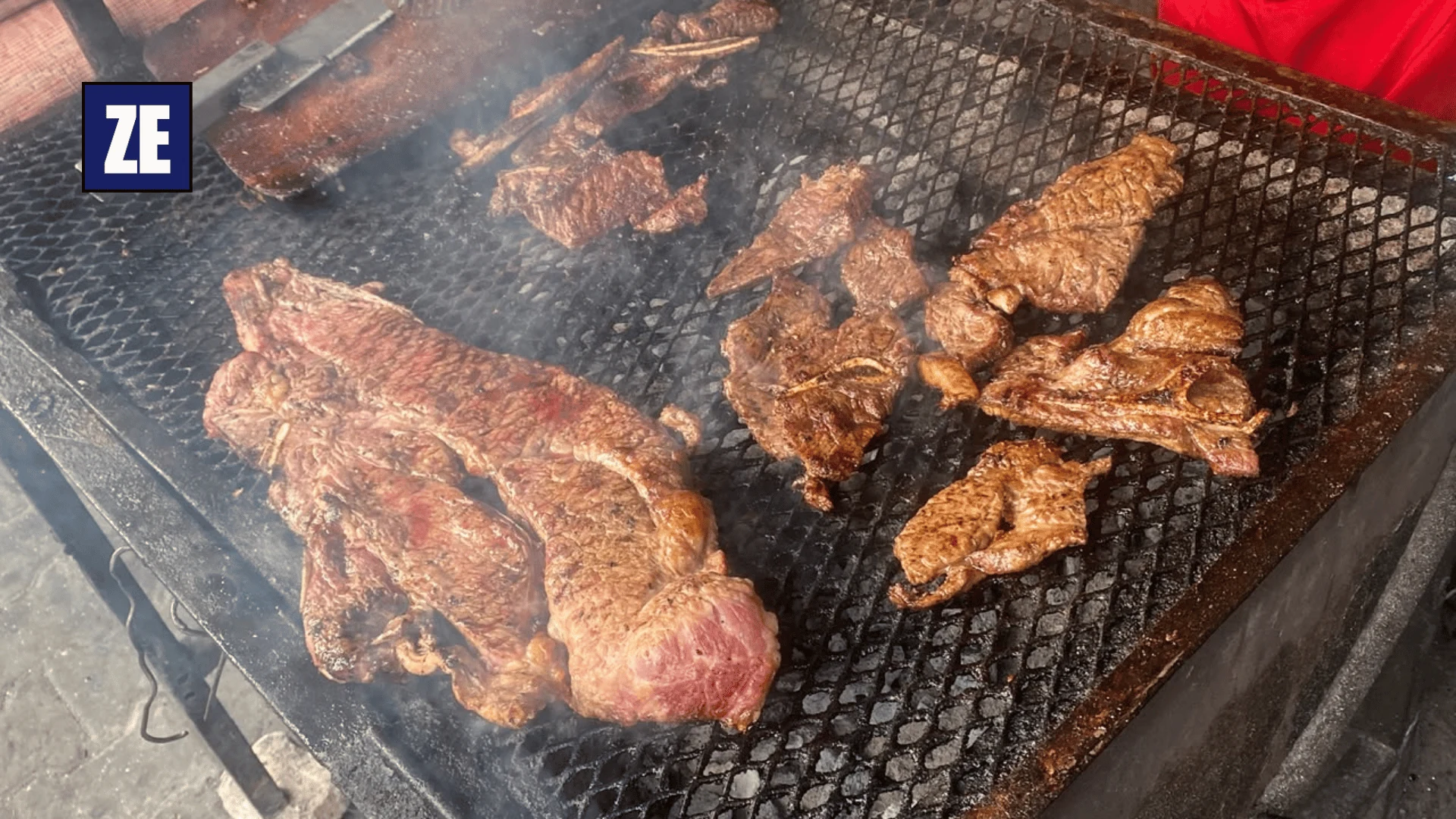 Cuts of meat cooking on a charcoal grill at Longacres Market in Lusaka