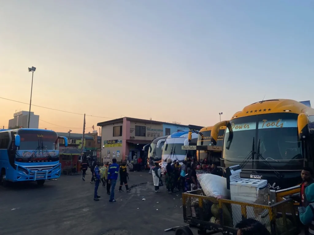 Coaches and travellers at Lusaka Intercity Bus Terminus in the early Sunday morning light