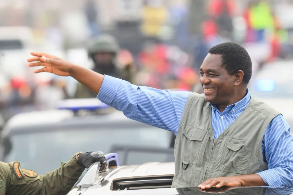 President Hakainde Hichilema waves to supporters from an open vehicle flanked by a security escort