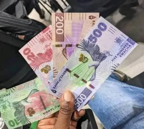 A hand holding fanned Zambian kwacha banknotes in K20, K50, K200 and K500 denominations