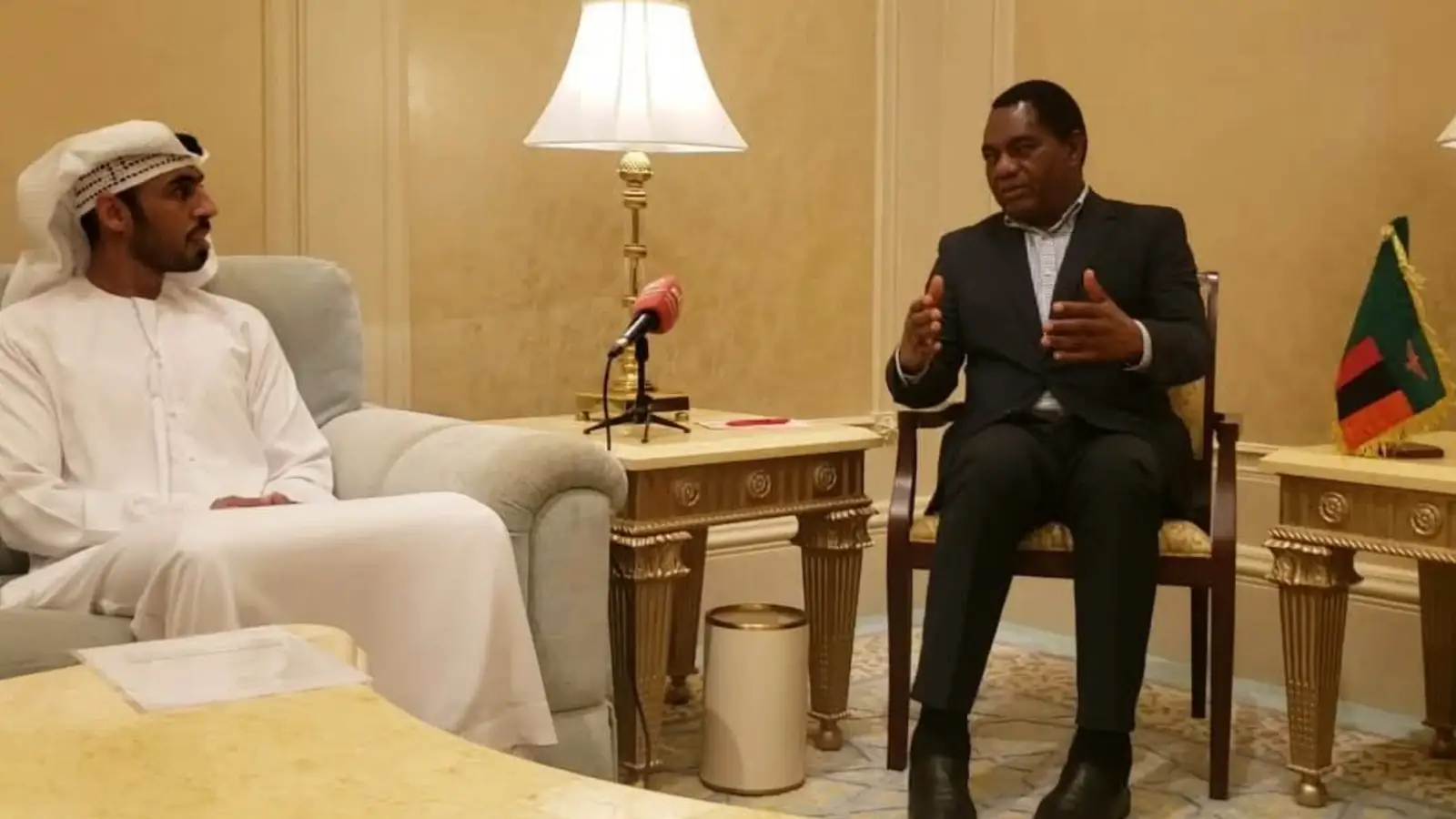 President Hakainde Hichilema speaks with IRH Chief Executive Ali Rashed Alrashdi in Abu Dhabi, with a Zambian flag on the side table