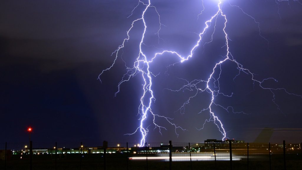Lightning bolts strike over a city skyline at night under dark storm clouds, illustrating Zambia's thunderstorm and strong wind warning for 27 September to 2 October 2026