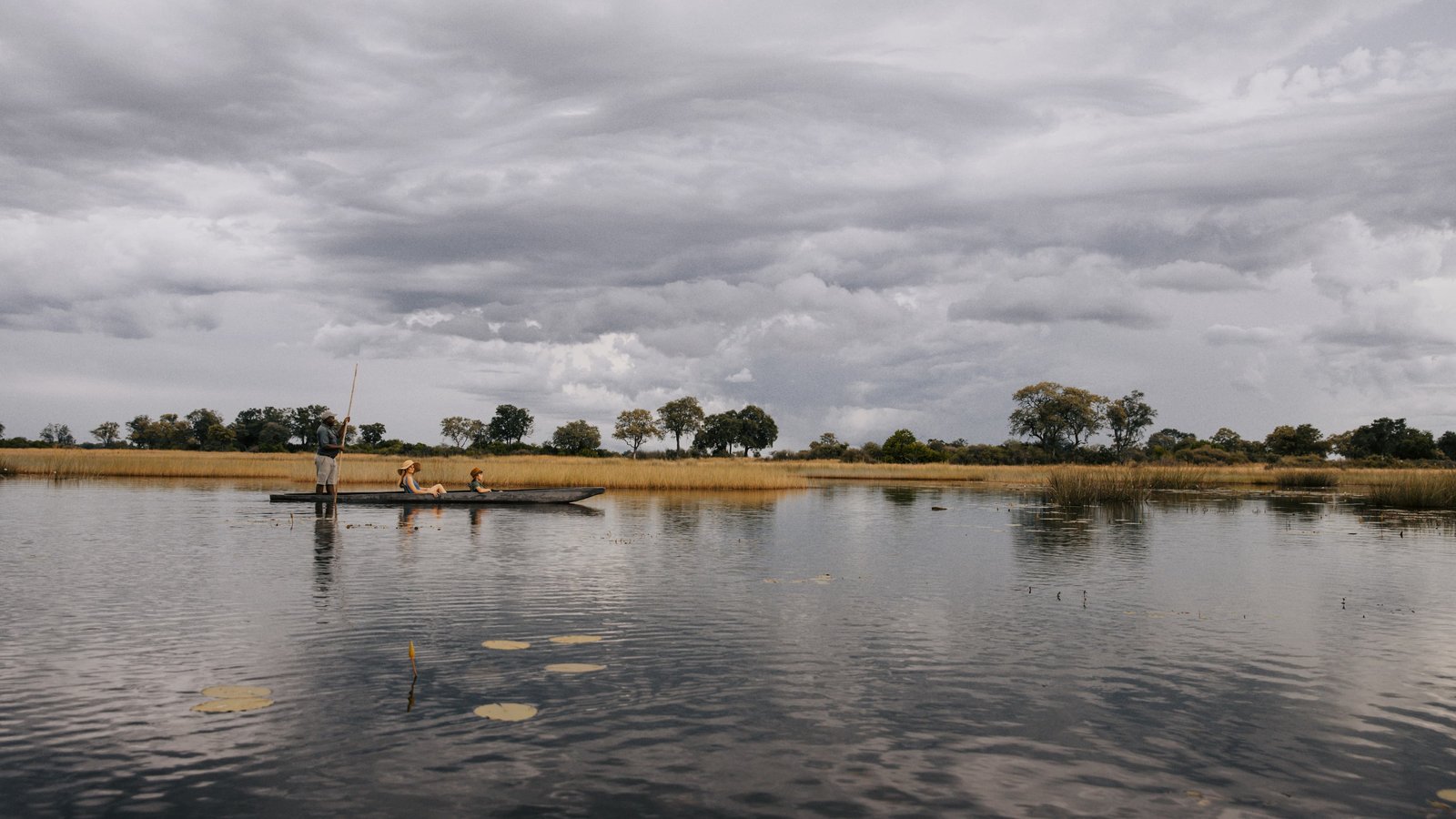 A boat crossing a floodplain under dark storm clouds in southern Africa, illustrating the water transport risk in Zambia's thunderstorm warning of 27 September to 2 October 2026