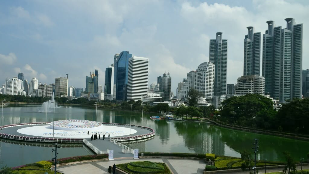 High-rise buildings overlooking a lake, landscaped gardens and a circular platform in Bangkok.