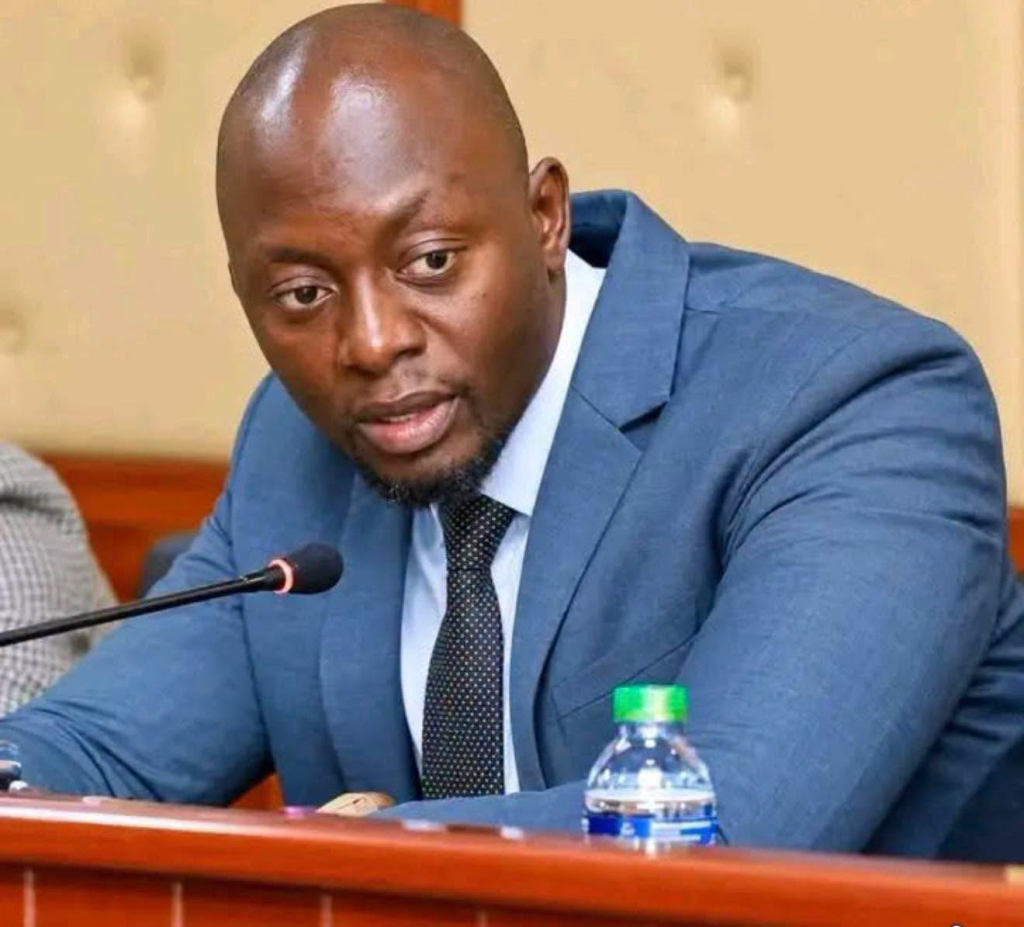 Emmanuel Jay Banda seated at a microphone in a blue suit
