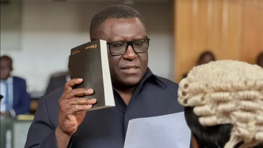 Official holding a Bible and reading the oath of office before a court officer in a wig at the Lusaka Mayor swearing-in