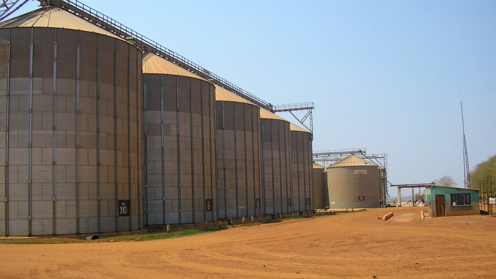 Row of grain silos beside a weighing bridge at a commercial farm in Mpongwe, Zambia, where harvested maize is stored before milling and sale